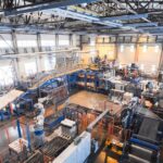 PTZ security camera overseeing large industrial manufacturing facility with robotics, conveyor systems, and heavy machinery — professional commercial CCTV installation by Apollo Technology & Cabling